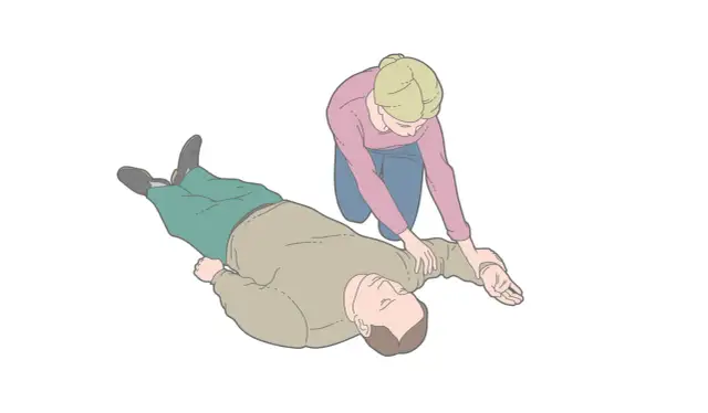 Kobieta klęczy obok nieprzytomnego mężczyzny i układa go w pozycji bocznej bezpiecznej.