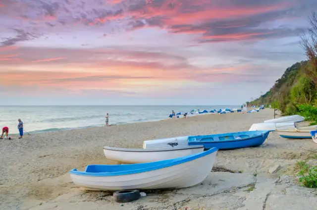Zachód słońca nad Morzem Czarnym, łodzie na plaży. Zastanawiasz się, ile kosztuje lot do Bułgarii?