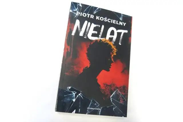 Okładka książki "Nielat" Piotra Kościelnego. Mroczna sylwetka postaci na tle czerwieni i pękniętego szkła.