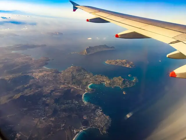 Widok z samolotu na wybrzeże Sardynii z turkusową wodą i zielonymi wyspami.