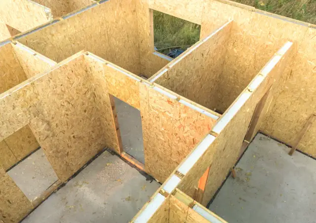 Budowa domu szkieletowego z płyt drewnopochodnych, co zamiast OSB. Widać zarys pomieszczeń i otwory okienne.