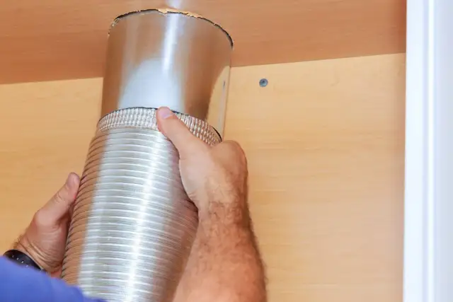 Dłoń montuje elastyczną rurę wentylacyjną do okapu. Jaka średnica rury do okapu jest potrzebna?