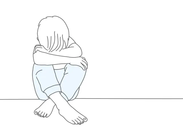 Ilustracja dziecka siedzącego ze zwieszoną głową i skrzyżowanymi nogami.