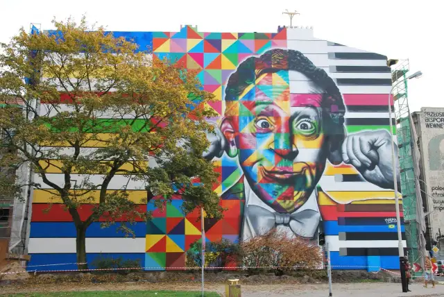Kolorowe murale w Polsce zdobią budynek. Twarz mężczyzny podzielona na geometryczne wzory i klawisze fortepianu.