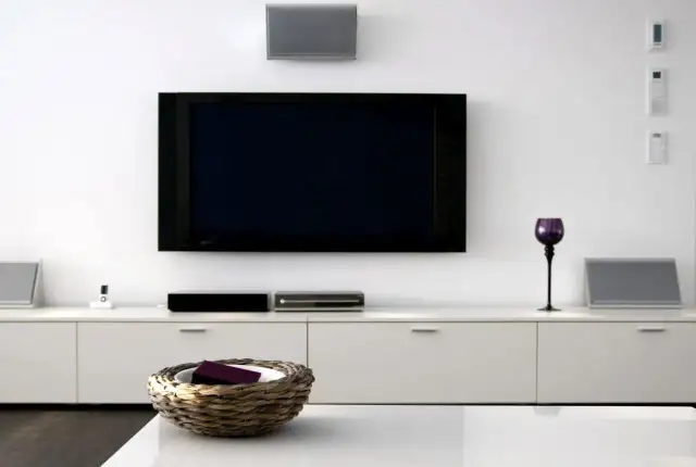 Nowoczesny salon z dużym telewizorem na ścianie, białymi meblami i dekoracjami.