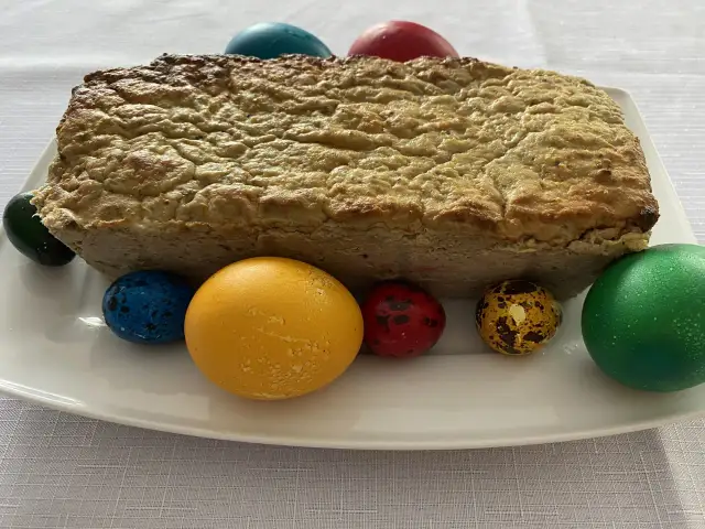 Pieczony pasztet bezglutenowy na białym talerzu z kolorowymi jajkami wielkanocnymi.