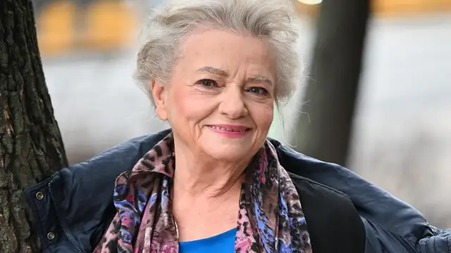 Uśmiechnięta Anna Seniuk, ikona polskich filmów, seriali i programów, w kolorowym szalu i granatowej kurtce.