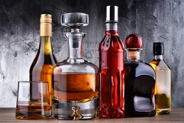 Karafka z koniakiem i inne butelki z brandy na drewnianym blacie.