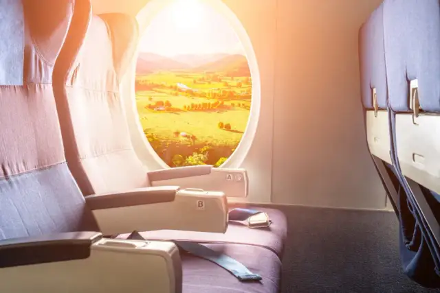 Komfortowe miejsca w samolocie lot. Widok na zielone pola i wzgórza przez okno.