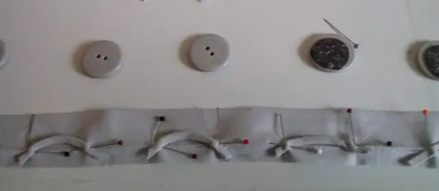 Przygotowanie pętelek do zapięcia swetra. Guziki i materiał z agrafkami czekają na zszycie.