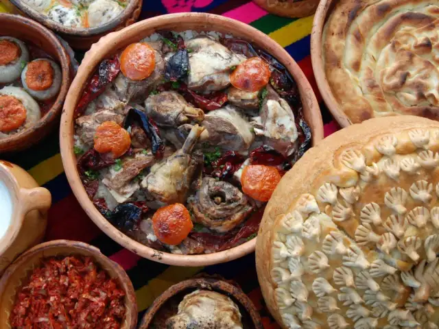 Bogactwo smaków kuchni bałkańskiej: pieczone mięso z ryżem, faszerowane cebule, chleb z ozdobami i ajvar.