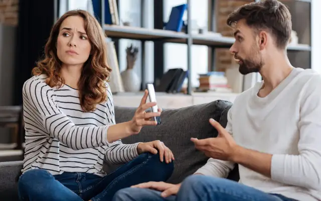 Kobieta z telefonem w dłoni patrzy z wyrzutem na mężczyznę, który gestykuluje. Czy to początek mikrozdrady?