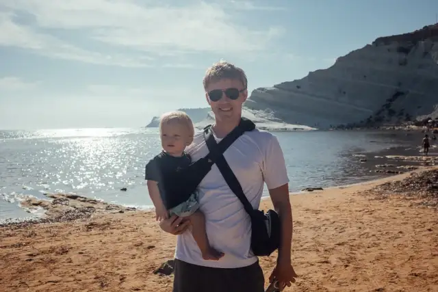 Ojciec z niemowlakiem na plaży, idealne miejsce, gdzie na wakacje z niemowlakiem. Słońce, morze i białe klify tworzą piękne tło.