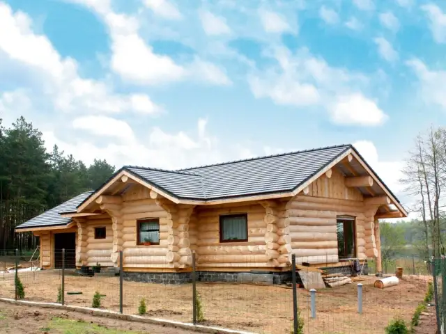 Dom z bali w budowie, z widocznymi belkami i dachem. Zastanawiasz się, ile trwa budowa domu z bali?