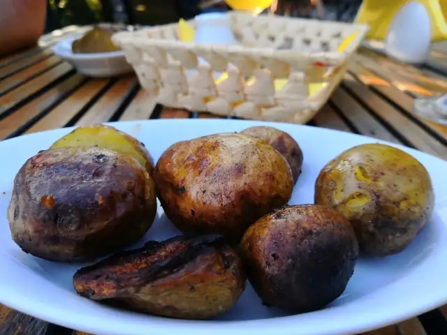 Talerz pieczonych ziemniaków na drewnianym stole, w tle koszyk i naczynia.