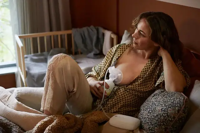 Kobieta odciąga mleko laktatorem, zastanawiając się, ile mleka odciągać laktatorem.