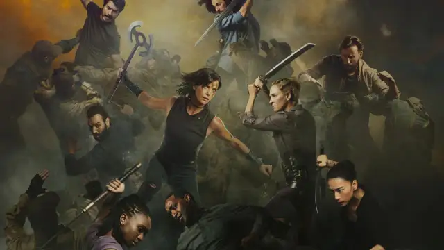 Grupa wojowników walczy w mgle. W centrum dwie kobiety z mieczami, a wokół nich inni walczący. To scena z filmu "The Old Guard 2".