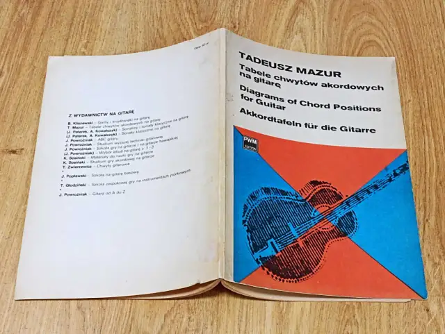Otwarta książka z tabelami chwytów gitarowych i schematycznym rysunkiem gitary.