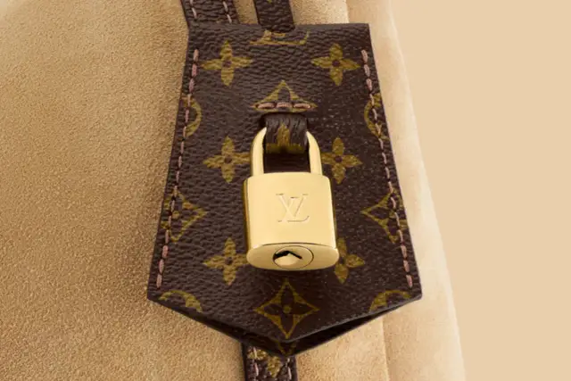 Złota kłódka z logo LV na brązowej skórze z monogramem Louis Vuitton.