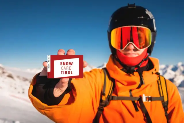 Narciarz w kasku i goglach pokazuje kartę "Snow Card Tirol". To jest skipass, który umożliwia dostęp do wyciągów.