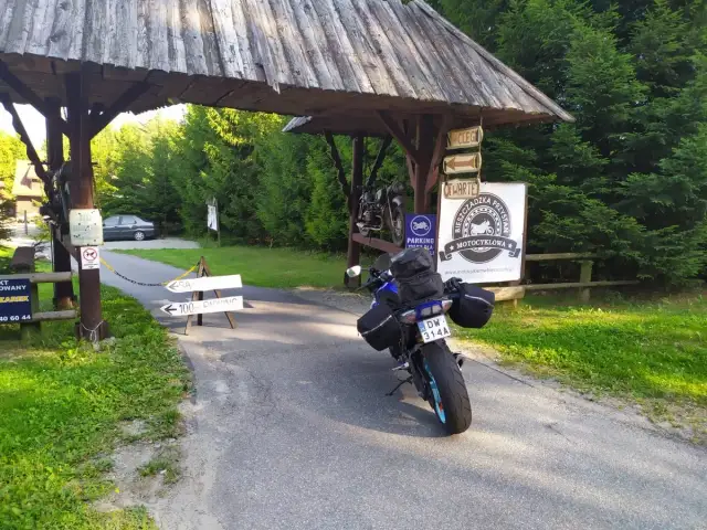 Motocykl czeka na dalszą podróż po Słowacji. Przy drogowskazie "100m parking" i znaku "Bieszczadzka Przystań Motocyklowa" zaczyna się przygoda.