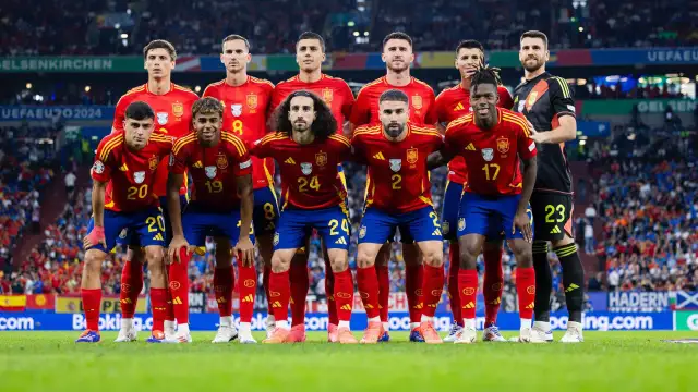 La selección española de fútbol posa en el campo. El equipo, con sus camisetas rojas y pantalones azules, muestra su unidad y determinación. Así ha quedado España en el fútbol, lista para la batalla.