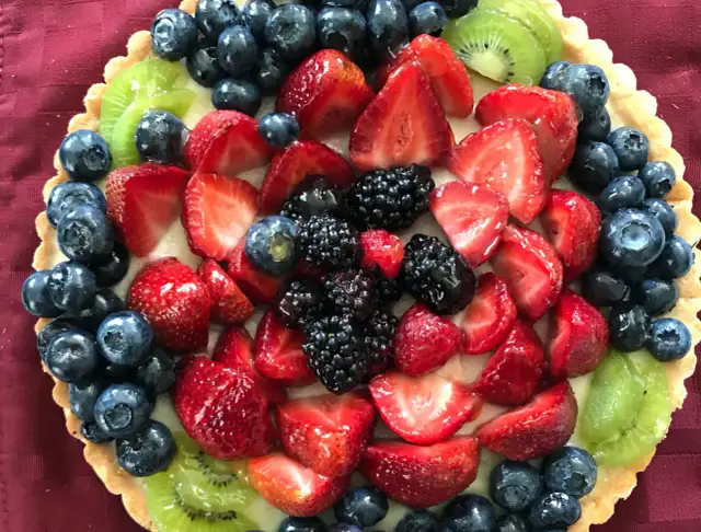 Kolorowa tarta z owocami: truskawki, borówki, jeżyny i kiwi.