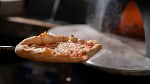 Gorąca pizza z serem i sosem pomidorowym wyjmowana z pieca.