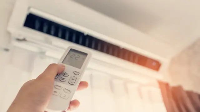 Dłoń trzymająca pilot do klimatyzacji z widoczną temperaturą 22 stopnie.