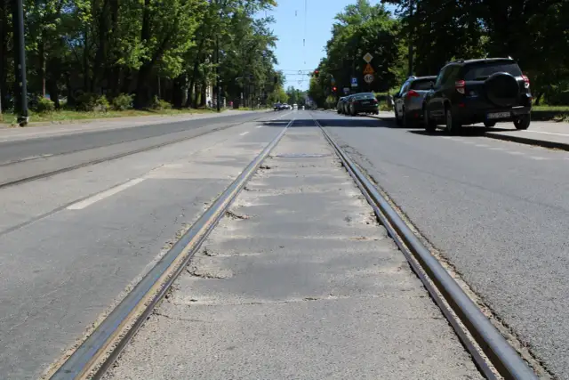 Torowisko tramwajowe na ulicy w Łodzi. Samochody stojące na poboczu sugerują utrudnienia w ruchu.