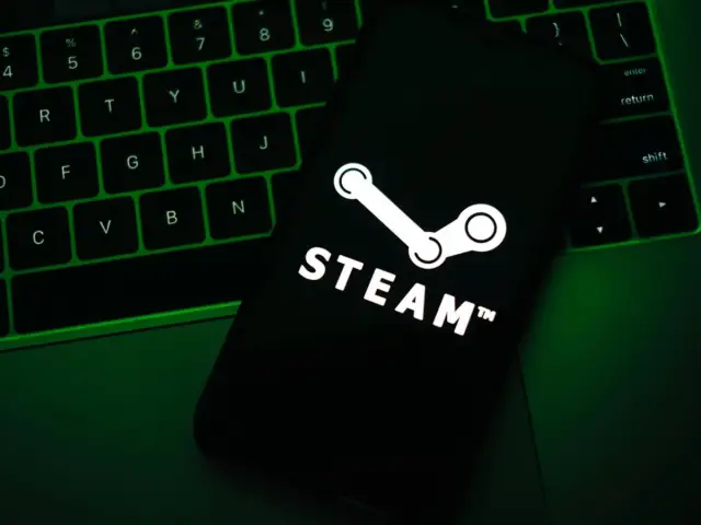 Telefon z logo Steam na tle zielonej klawiatury.
