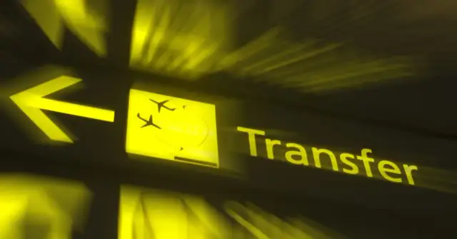 Żółty znak lotniskowy z ikoną samolotu i napisem "Transfer". Czy można opuścić lotnisko podczas przesiadki?