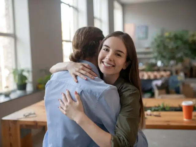 Uśmiechnięta dziewczyna mocno przytula przyjaciela. To szczere podziękowanie za pomoc i wsparcie.