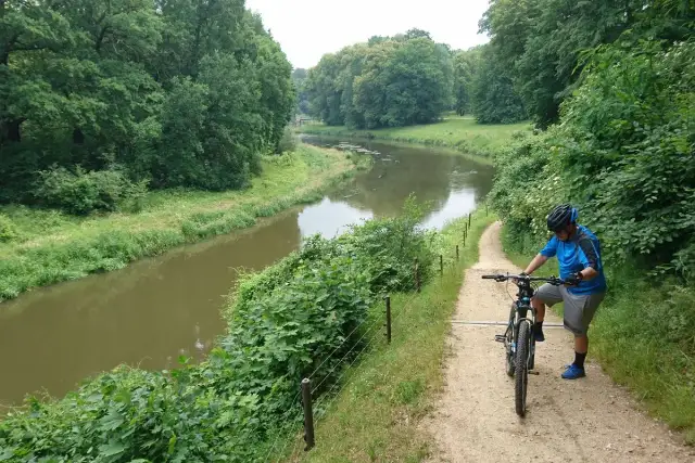 Rowerzysta na ścieżce w Parku Mużakowskim. Malownicze trasy rowerowe wzdłuż rzeki zachęcają do aktywnego wypoczynku.