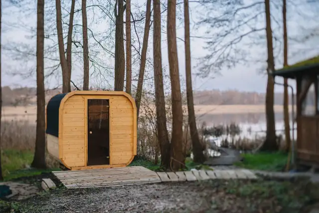 Drewniana sauna w lesie nad jeziorem.