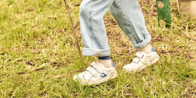 Białe sneakersy na rzepy, idealne na spacer po trawie. To wygodne buty dla aktywnych.