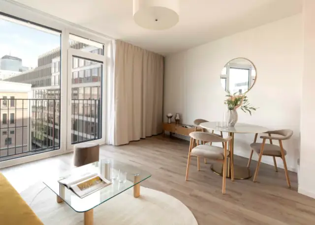 Nowoczesne mieszkanie inwestycyjne co to znaczy? Jasny salon z jadalnią, balkonem i widokiem na miasto.