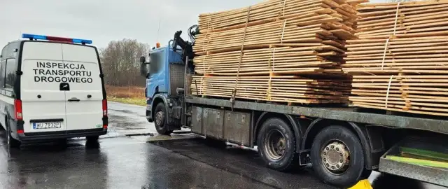 Samochód Inspekcji Transportu Drogowego obok ciężarówki z drewnem.
