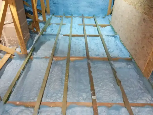 Ocieplenie poddasza pianką PUR, widoczne drewniane belki konstrukcyjne i izolacja.