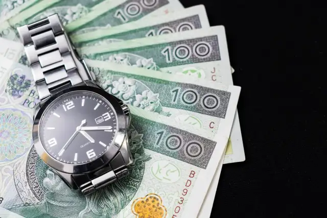 Zegarek na stosie polskich banknotów 100 zł.