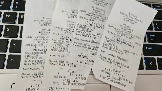 Paragon fiskalny z autostrady A2 na klawiaturze laptopa.