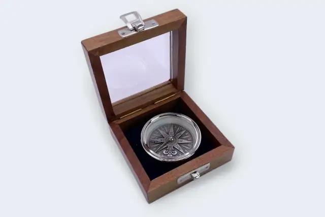 Otwarta drewniana szkatułka z ozdobnym kompasem w środku.