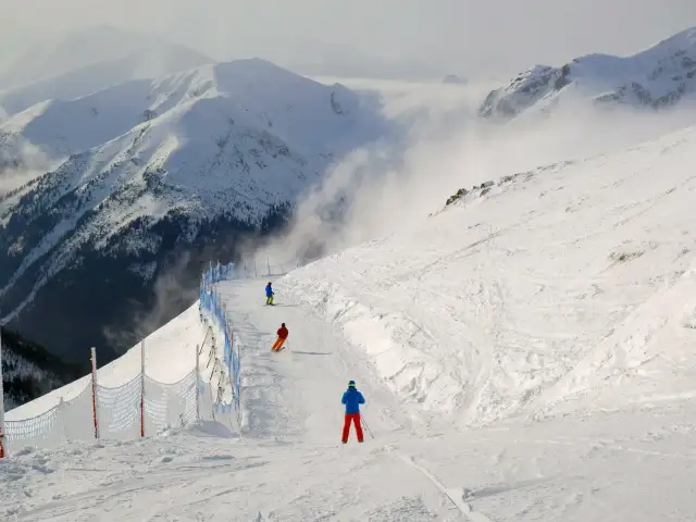 Ostatni zjazd na stoku, kiedy kończy się sezon narciarski. Trzech narciarzy zjeżdża po ośnieżonych górach, otoczonych mgłą.