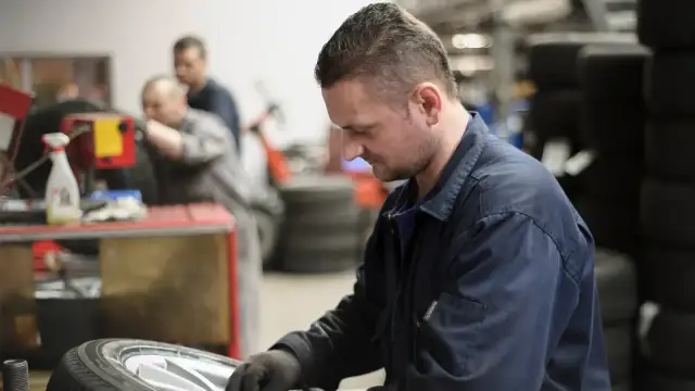 Mechanik w warsztacie naprawia oponę samochodową.