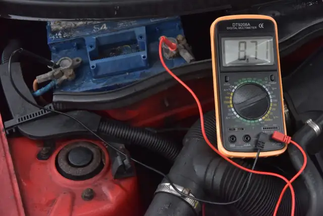 Sprawdzanie akumulatora multimetrem, by dowiedzieć się, jak odpalić auto z rozładowanym akumulatorem. Wynik 8.71V wskazuje na problem.