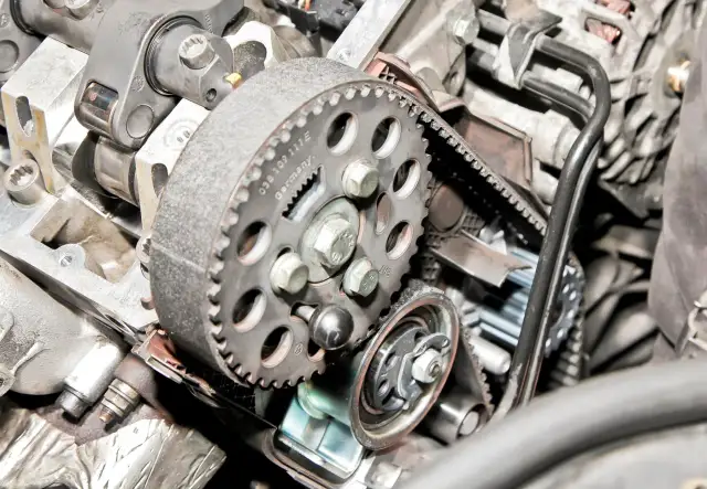 Widok silnika z paskiem rozrządu i kołem zębatym. Widać fragment czujnika położenia wału rozrządu.