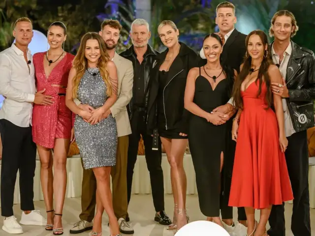 Uśmiechnięci uczestnicy Love Island 7 pozują do zdjęcia. Widać ich w eleganckich strojach, gotowych na kolejne wyzwania w willi.