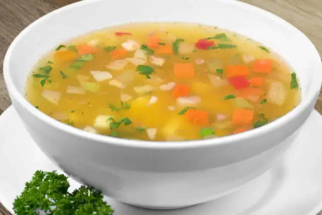 Miseczka zupy jarzynowej z widocznymi kawałkami warzyw i natką pietruszki.