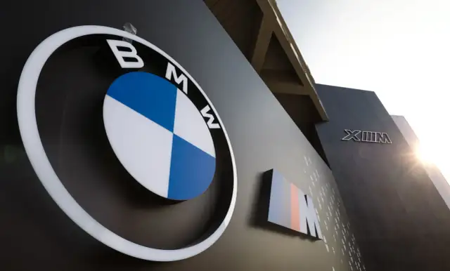 Logo BMW i oznaczenie M, symbole niemieckich marek samochodów, na ciemnej ścianie budynku.