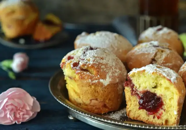Puszyste muffinki z dżemem, posypane cukrem pudrem, kuszą swoim domowym wyglądem.